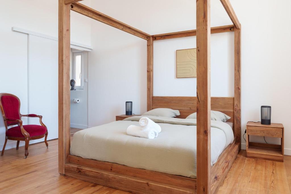 Chambre 1 avec lit à baldaquin en bois et fauteuil rouge