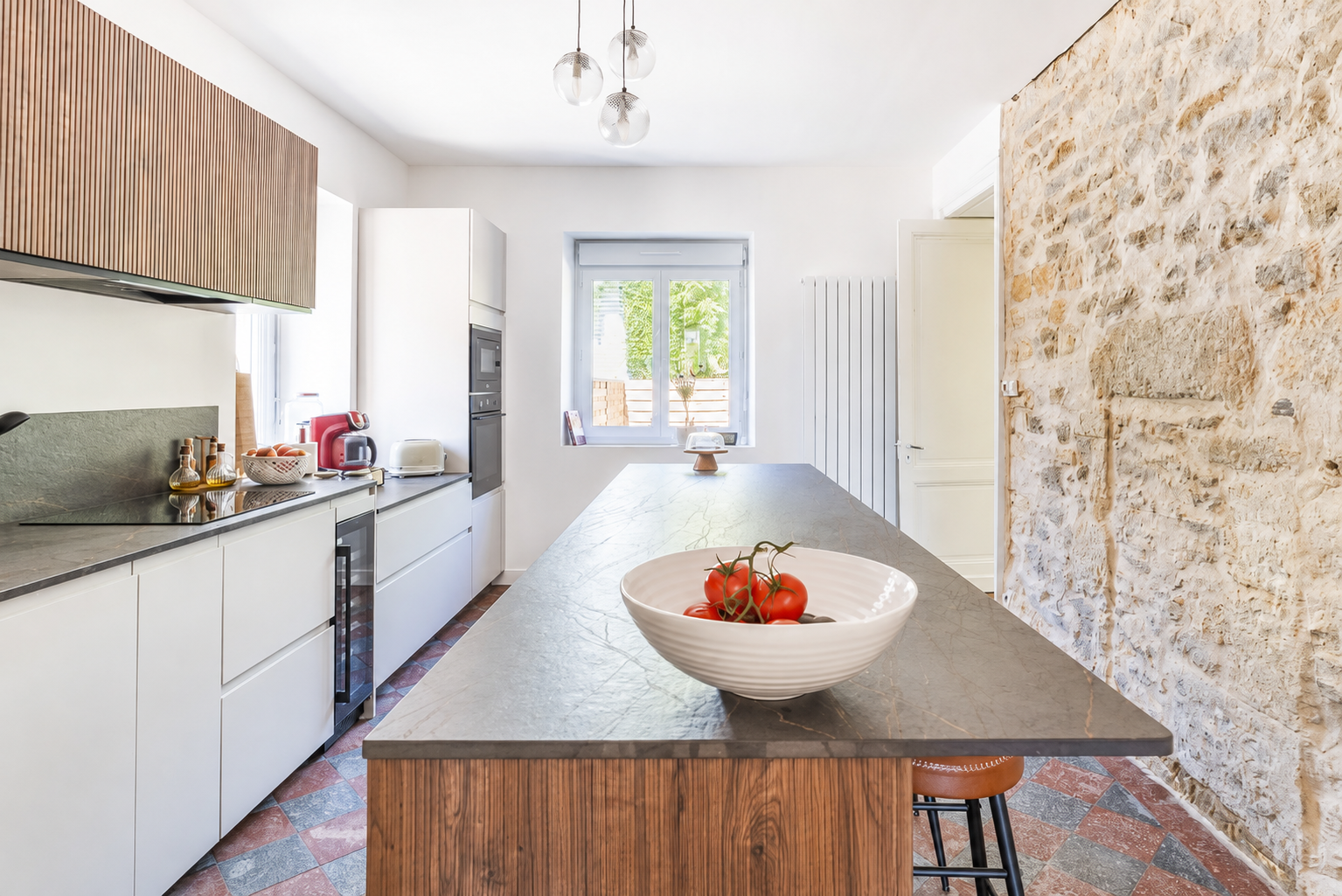 Cuisine équipée avec mur en pierre et îlot central
